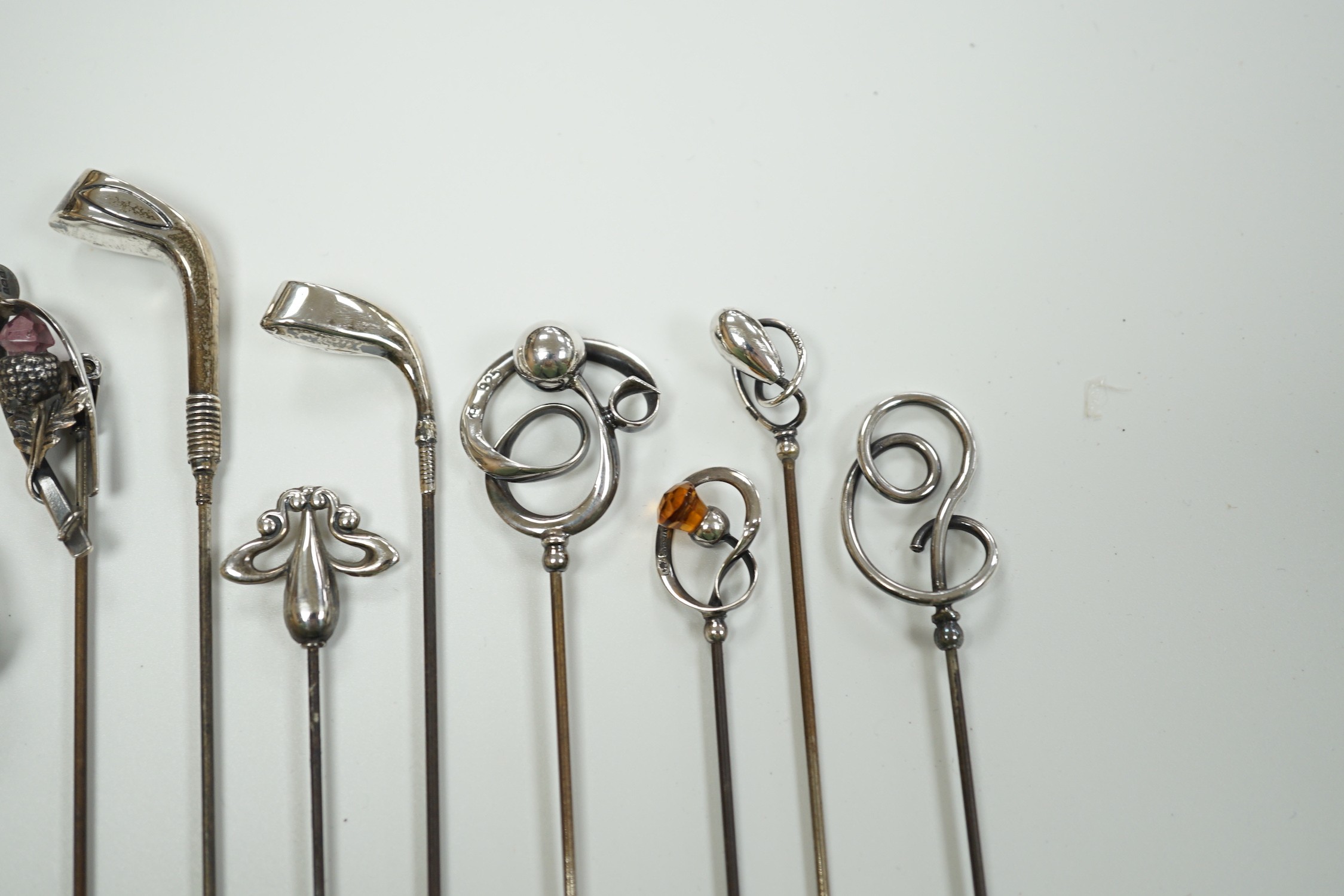 A collection of thirteen assorted early 20th century and later white or yellow metal hat pins, including four by Charles Horner including teddy bear and two silver golf club, longest 31.5cm.